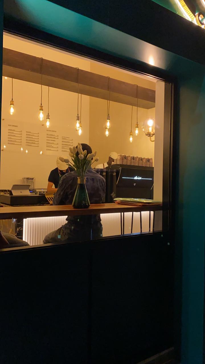 ARC Design café interior project in Dubai showing warm lighting, wooden ceiling beams, and modern hanging bulbs