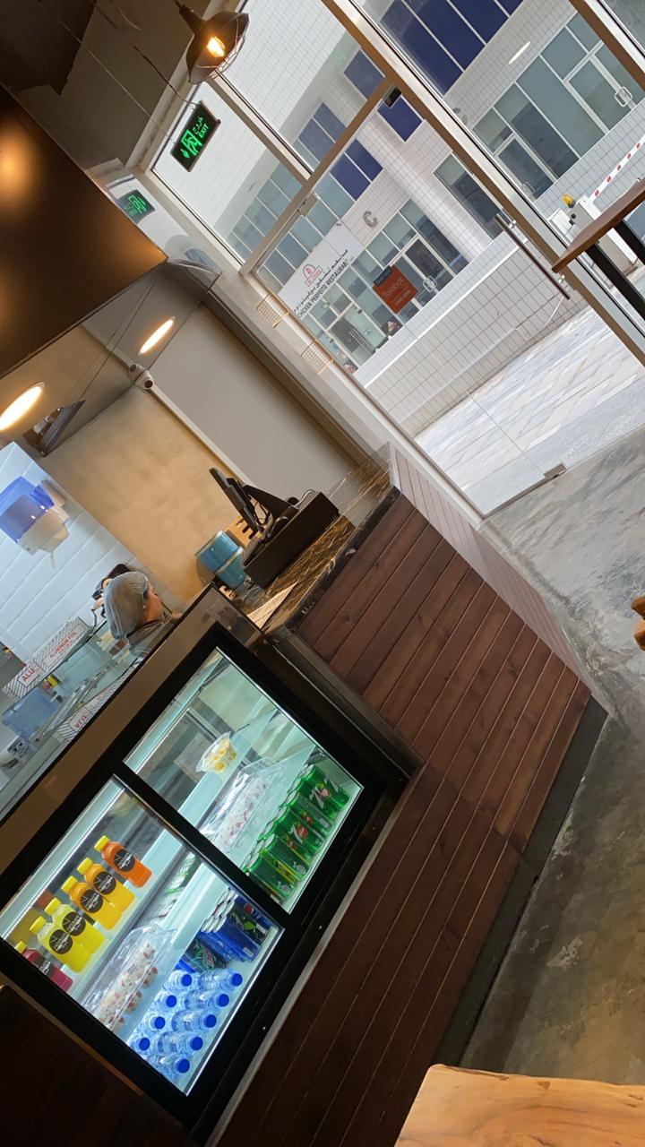Modern cafe interior with beverage display Modern coffee shop interior design with wooden counter and glass fridge – ARC Design Dubai